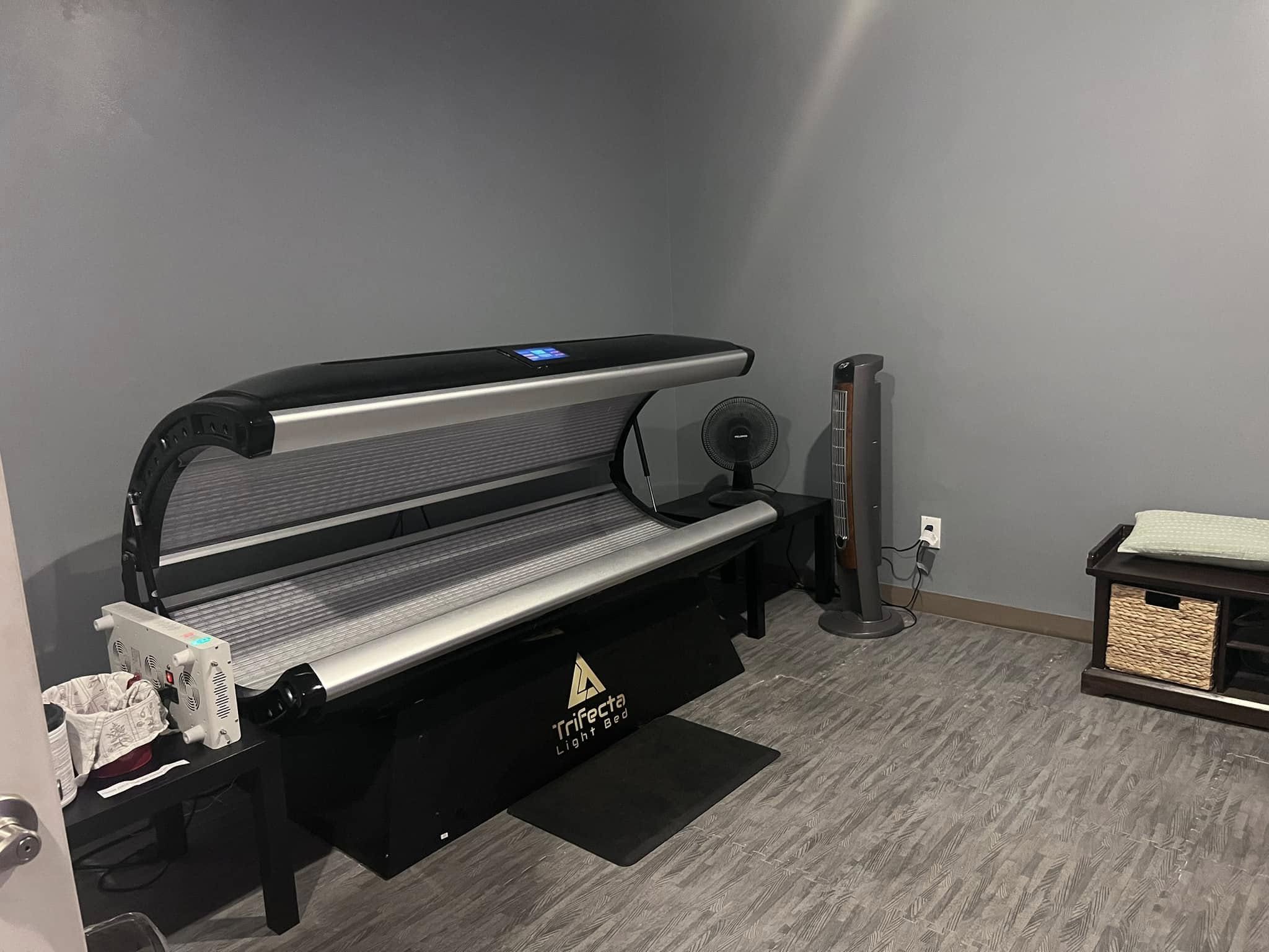 Trifecta Red Light Therapy bed open and ready for a session, branded equipment